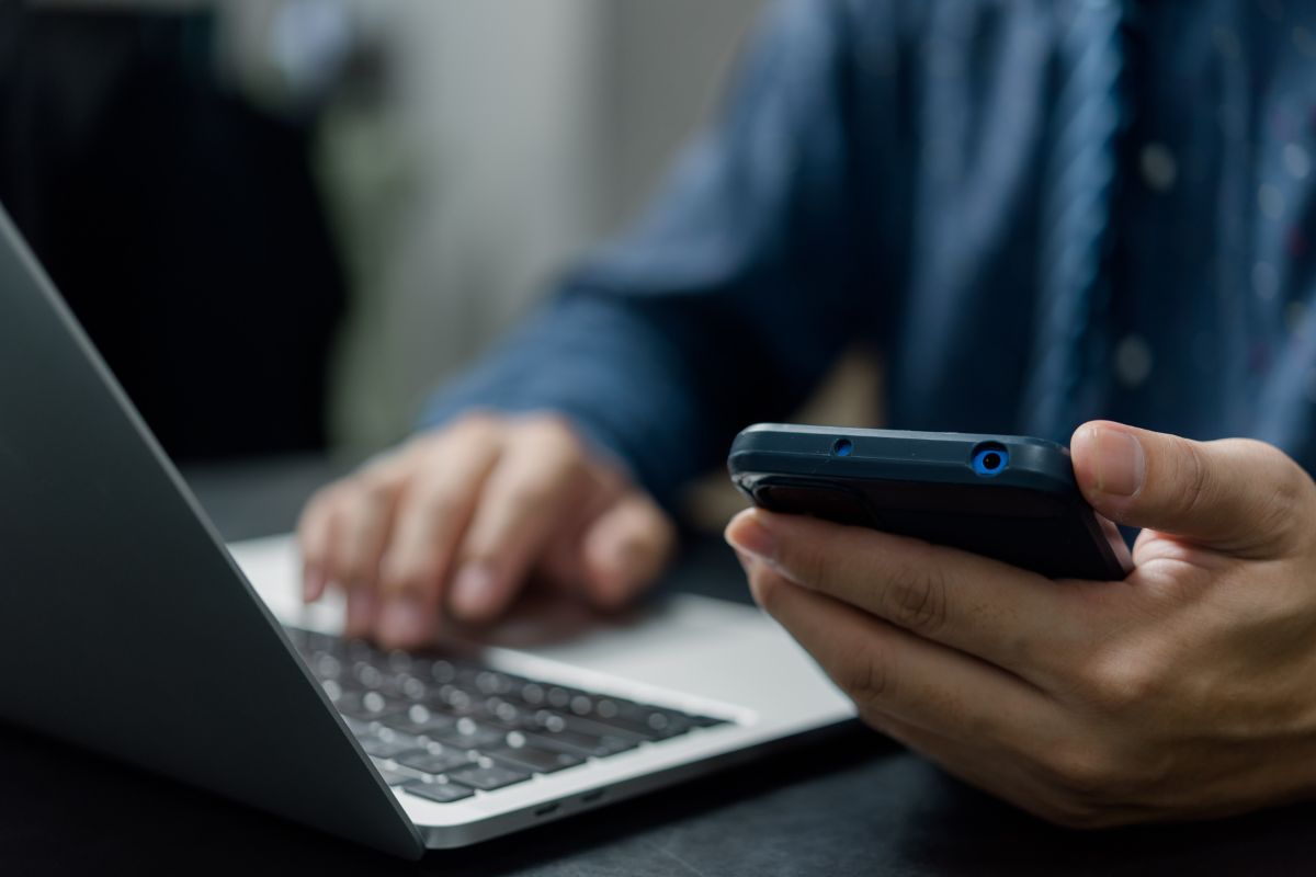 Person using a phone and laptop to make an enquiry